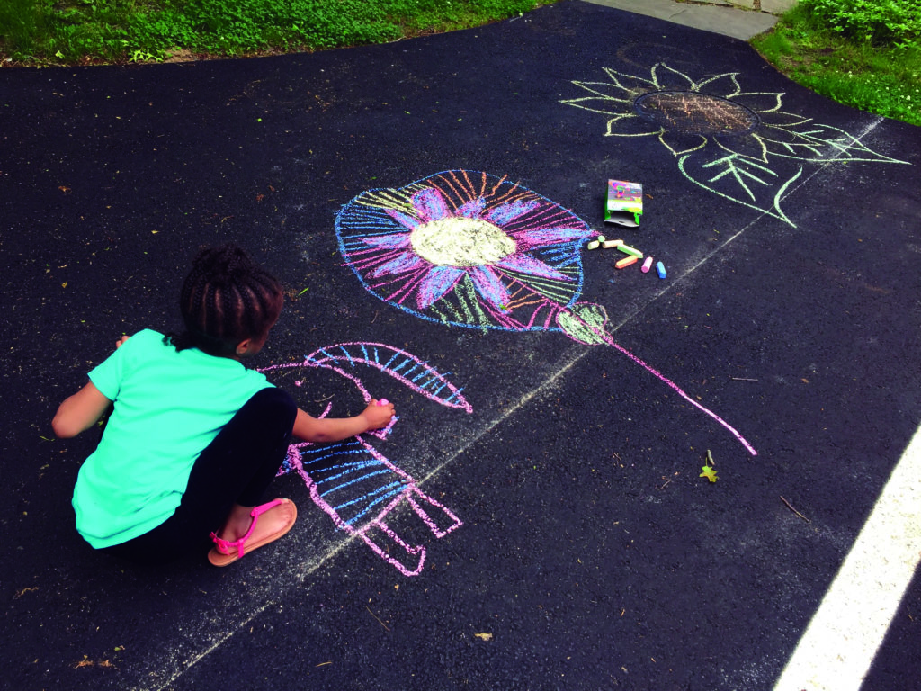 Girl drawing on pavement with chalk.